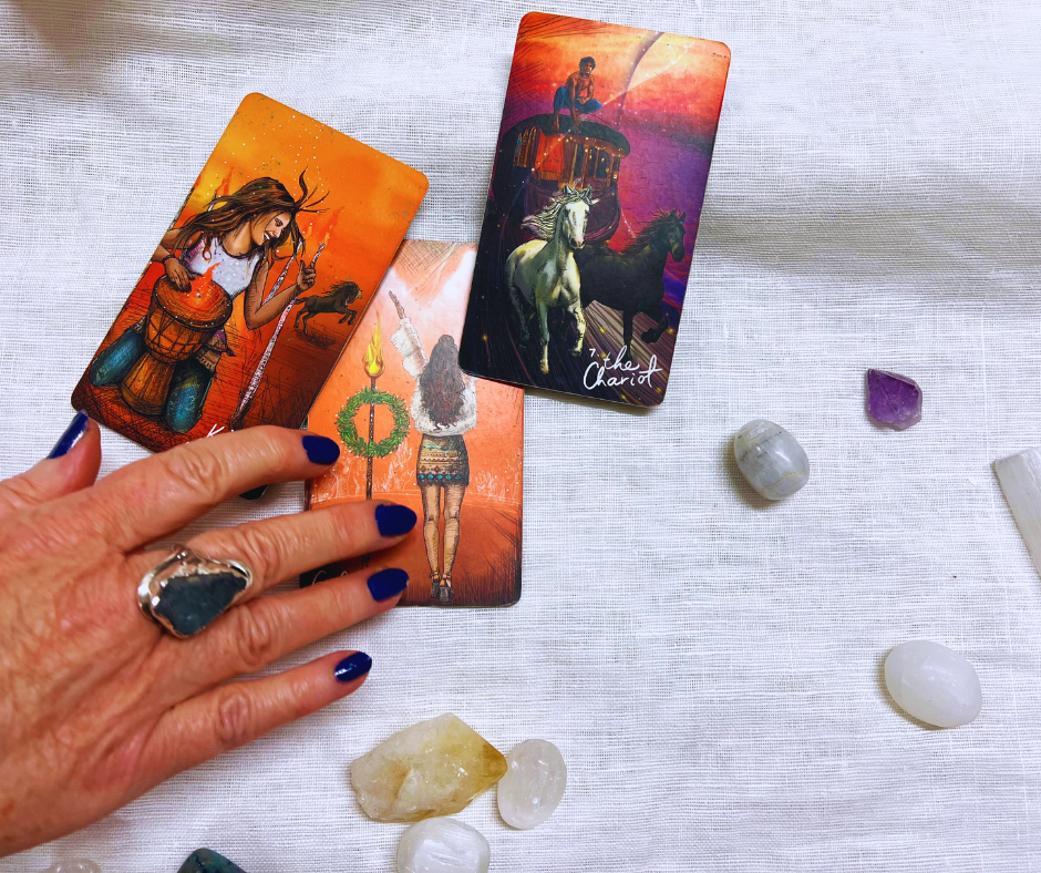 Photo of woman's hand on 3 tarot cards with surrounding crystals